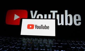 Close-up of YouTube logo displayed on a laptop screen in a dark environment.