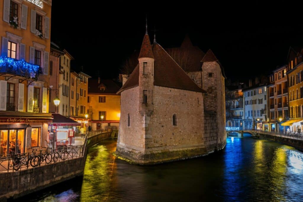 Captivating night scene of the iconic Annecy castle surrounded by illuminated canals.