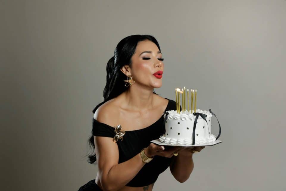 Elegant woman blowing out candles on a stylish birthday cake.