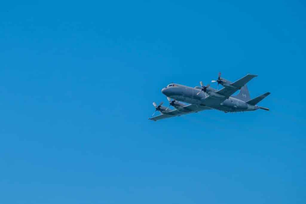 Propeller military aircraft soaring against a bright blue sky, showcasing aviation technology.