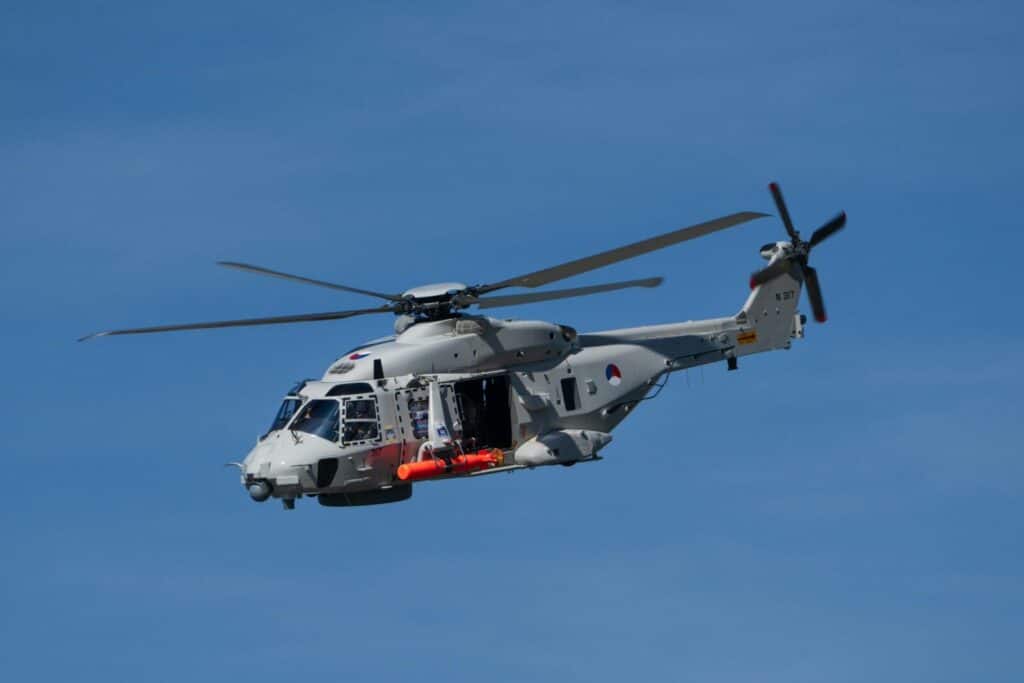 A military helicopter flying in a clear blue sky, showcasing aviation technology.