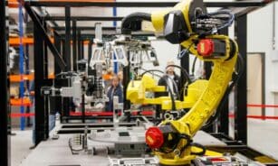 Close-up of a yellow industrial robotic arm in action at a modern manufacturing facility.