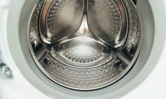 Detailed view of a clean, modern washing machine drum, showcasing shiny stainless steel interior.
