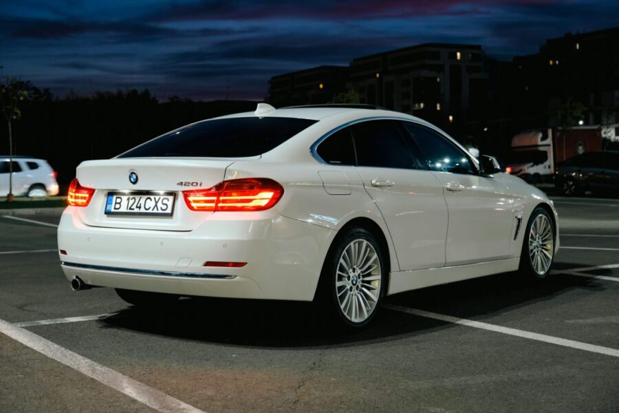 White BMW 420i parked in an urban area at night. Elegance and automotive style captured beautifully.