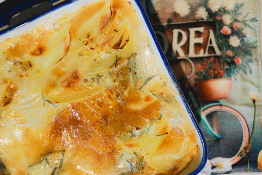 A rich and creamy potato gratin freshly baked, golden and crispy in a ceramic dish.
