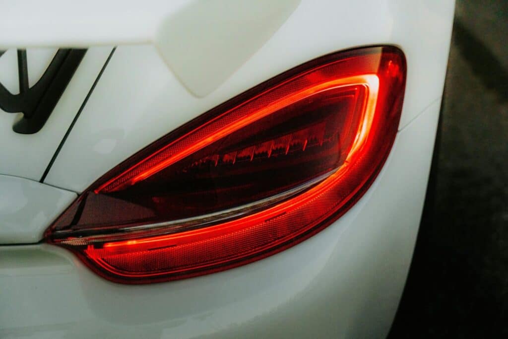 Detailed view of car tail light glowing red, captured during daylight.