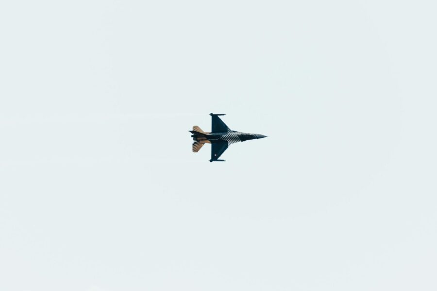 High-altitude jet fighter performing aerial maneuvers against a clear sky backdrop.