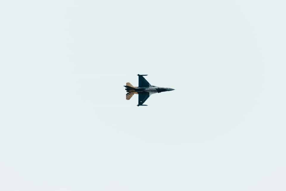 High-altitude jet fighter performing aerial maneuvers against a clear sky backdrop.