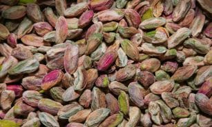 A high-resolution close-up of colorful unshelled pistachios, showcasing their natural texture and vibrant hues.