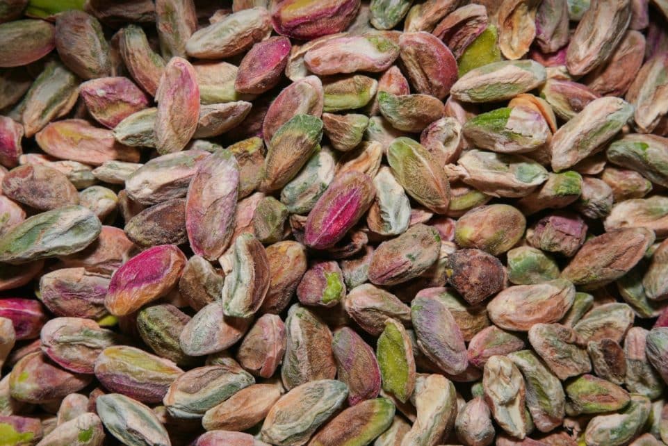 A high-resolution close-up of colorful unshelled pistachios, showcasing their natural texture and vibrant hues.