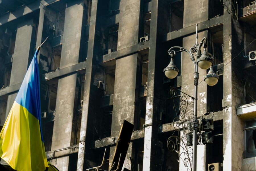 A damaged building in Kyiv, Ukraine with the Ukrainian flag displayed prominently.