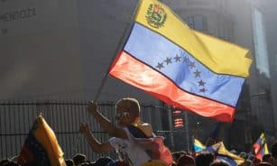 A young boy waves the Venezuelan flag during a vibrant street protest.