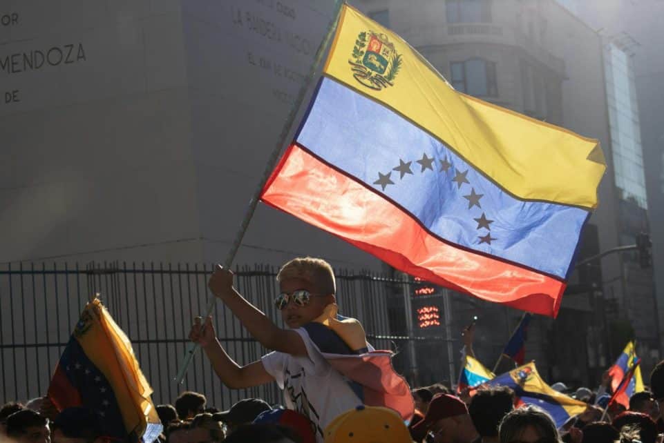 A young boy waves the Venezuelan flag during a vibrant street protest.