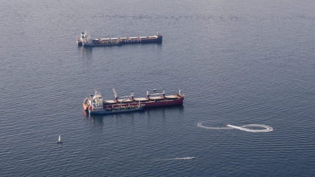 Aerial shot of two cargo ships in Gibraltar waters with boats nearby, showcasing maritime activity.