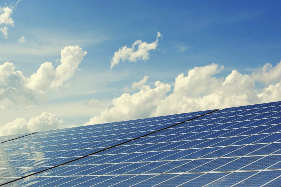 Sleek modern solar panels under a vibrant blue sky with clouds, symbolizing clean energy.