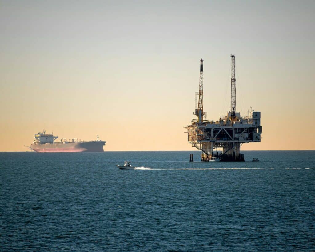 Offshore oil platform with container ship in tranquil sea during daytime.