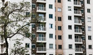 Exterior view of a modern apartment building with balconies and a tree, showcasing urban architecture.