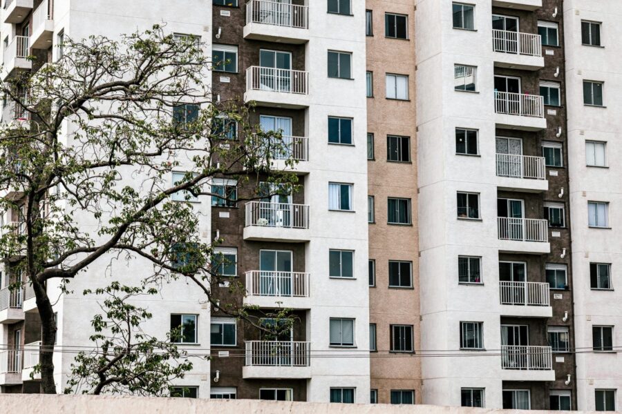 Exterior view of a modern apartment building with balconies and a tree, showcasing urban architecture.