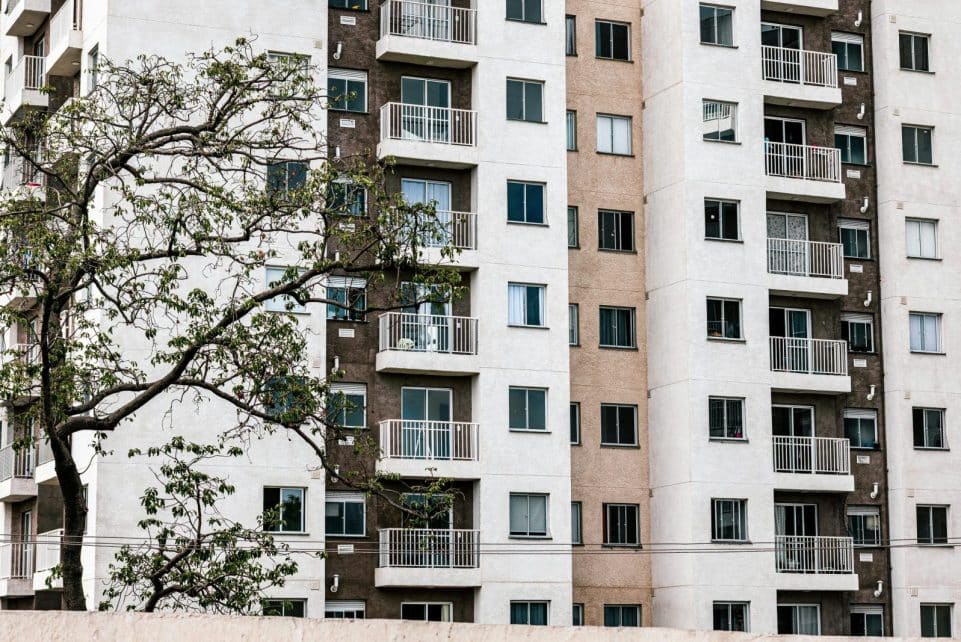 Exterior view of a modern apartment building with balconies and a tree, showcasing urban architecture.