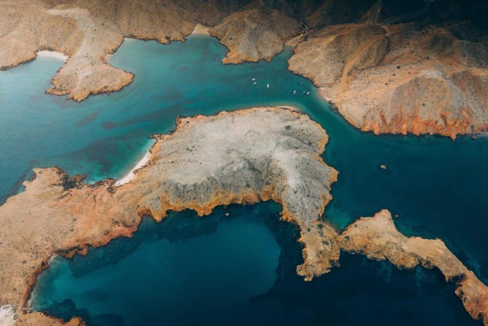 Stunning aerial view of a rugged coastal landscape in Oman showcasing turquoise waters and arid terrain.