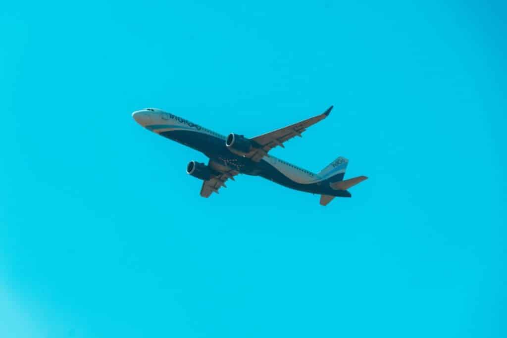 A commercial airplane soars through a clear, cloudless sky, symbolizing global travel and aviation.