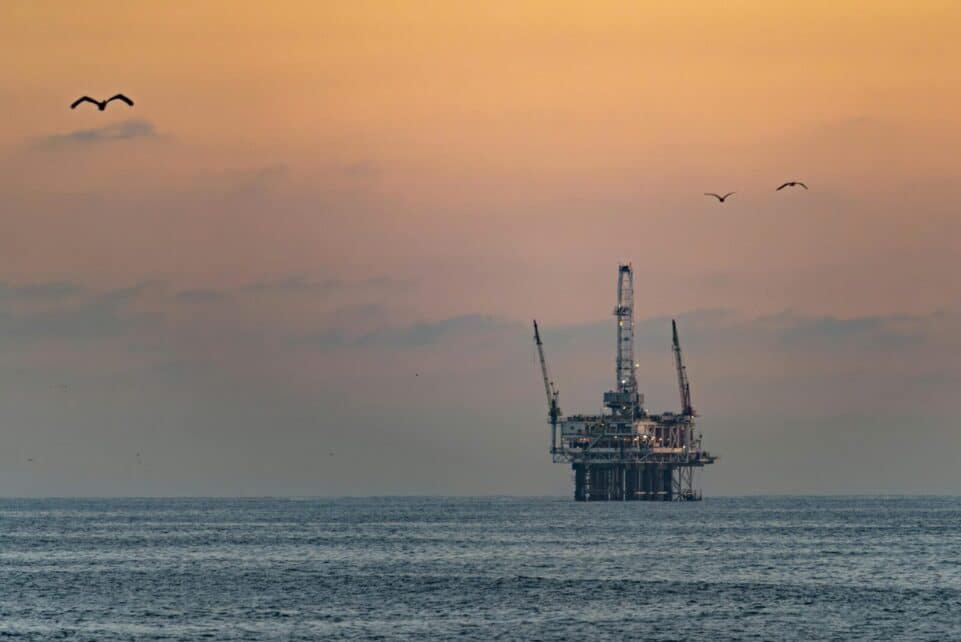 Oil platform silhouetted against a vibrant sunset in Huntington Beach, California.