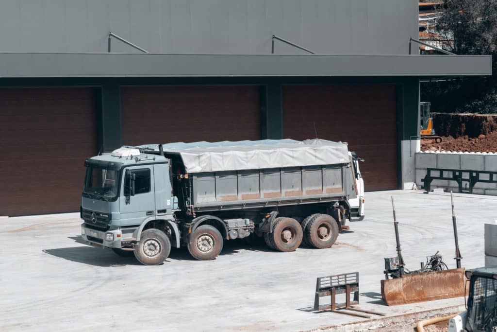 A large dump truck parked at an industrial construction site near a building.