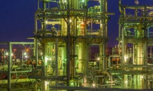 Illuminated industrial gas facility in Dahej, Gujarat, showcasing complex structures under a night sky.