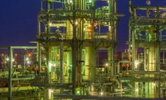 Illuminated industrial gas facility in Dahej, Gujarat, showcasing complex structures under a night sky.