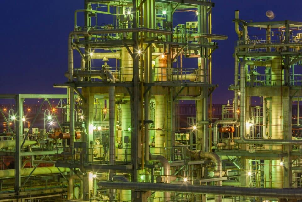 Illuminated industrial gas facility in Dahej, Gujarat, showcasing complex structures under a night sky.