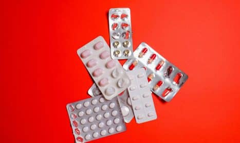 Blister packs with assorted pills over a vibrant red surface. Ideal for healthcare themes.