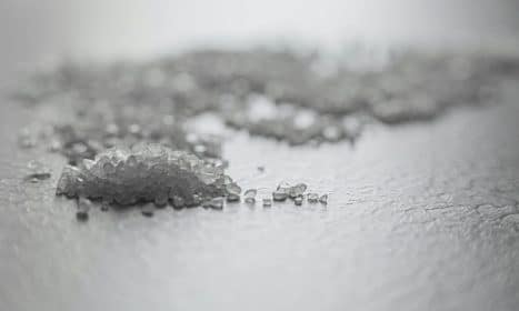 Detailed shot of coarse rock salt scattered on a textured surface.