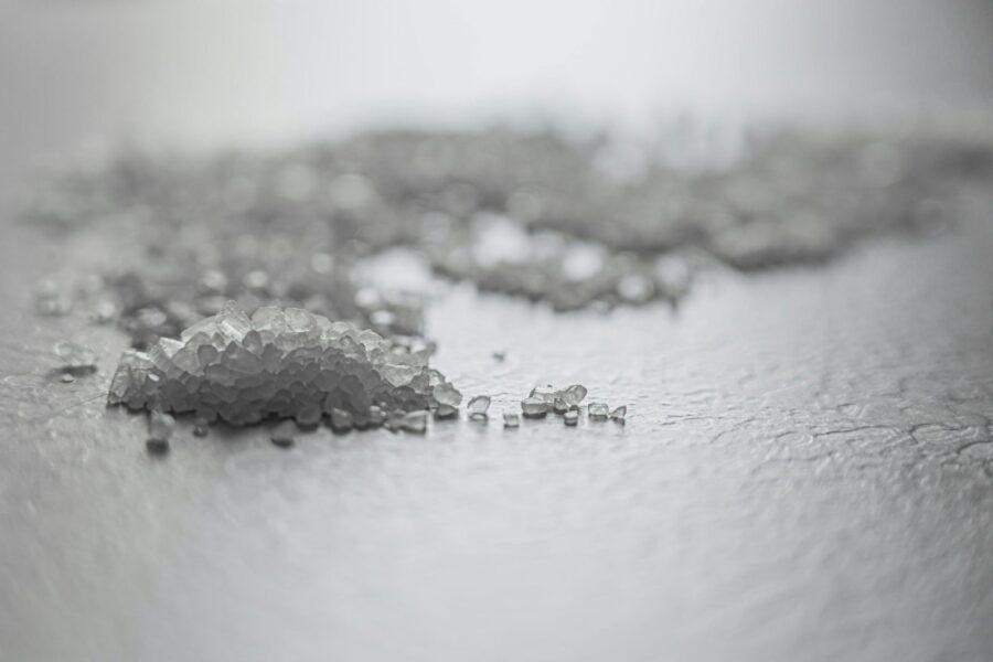 Detailed shot of coarse rock salt scattered on a textured surface.