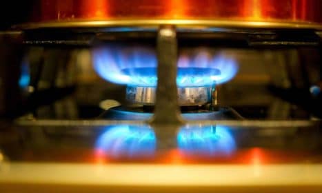 Close-up of a blue flame on a gas stove burner, showcasing kitchen heat and cooking.