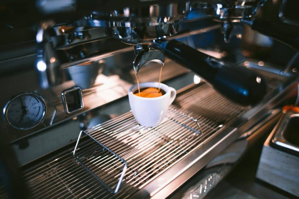 Close-up view of espresso being brewed into a cup using a professional coffee machine in a café.