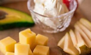 A delicious cheese platter featuring assorted cheeses, fresh fruit, and creamy cheese, ideal for a gourmet snack.
