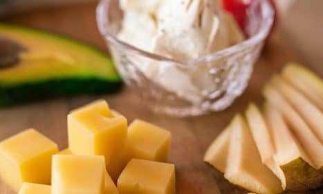 A delicious cheese platter featuring assorted cheeses, fresh fruit, and creamy cheese, ideal for a gourmet snack.
