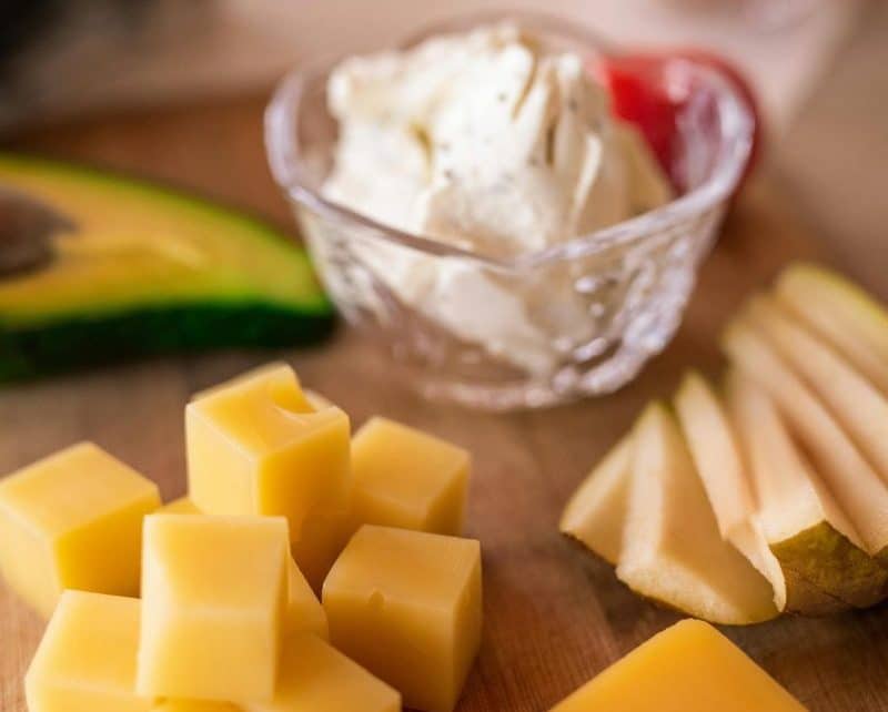 A delicious cheese platter featuring assorted cheeses, fresh fruit, and creamy cheese, ideal for a gourmet snack.