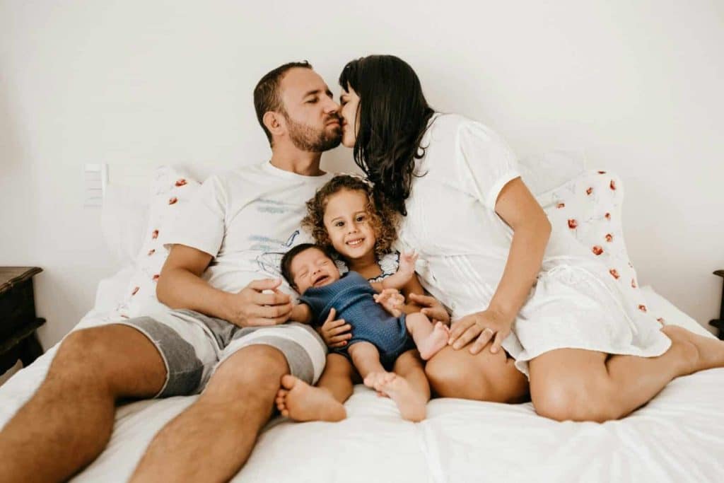 Happy family relaxing and enjoying quality time on a cozy bed, expressing love and togetherness.