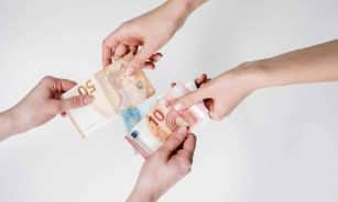 Two pairs of hands exchanging Euro banknotes, symbolizing finance and transaction.