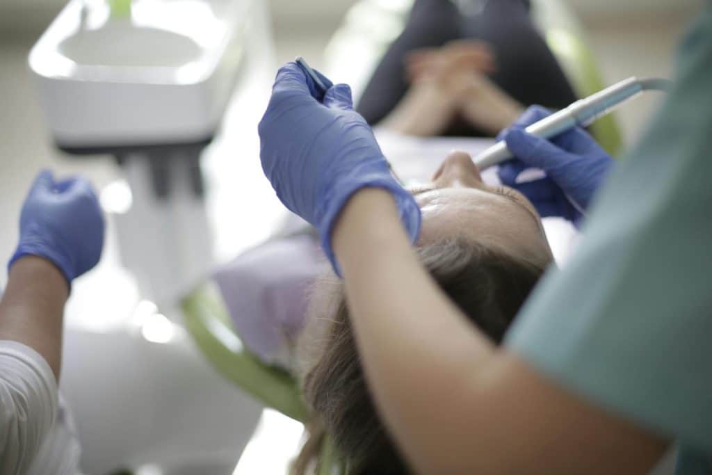 Patient undergoing dental procedure with dentist in modern clinic, focusing on oral care.