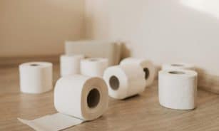 A neat arrangement of toilet paper rolls on a wooden floor, indoor setting.