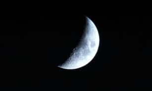 A detailed view of the crescent moon against a dark night sky, showcasing lunar craters.