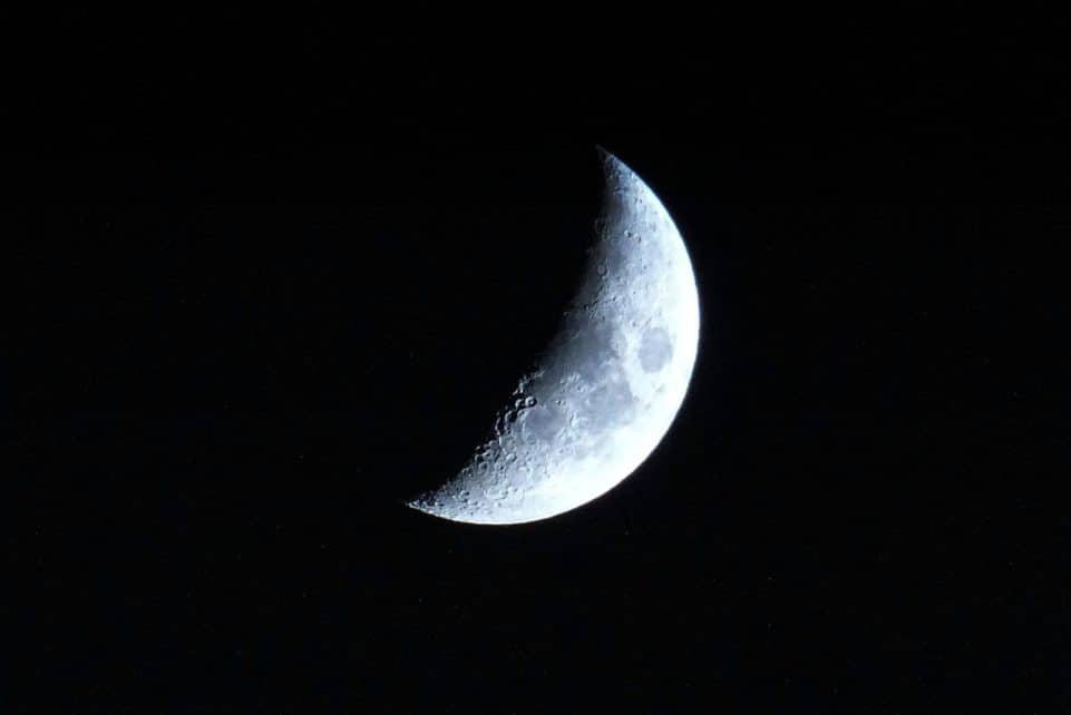 A detailed view of the crescent moon against a dark night sky, showcasing lunar craters.