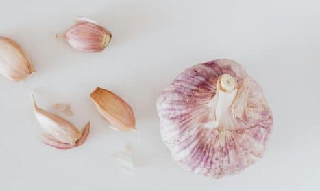 From above closeup of big whole garlic and set of cloves placed on white surface