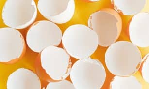 A top-down view of empty eggshells on a bright yellow surface, creating a minimalist aesthetic.