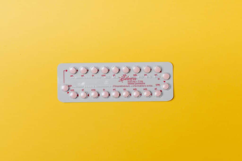 Close-up of a blister pack of pink pills on a vivid yellow background for medication concept.