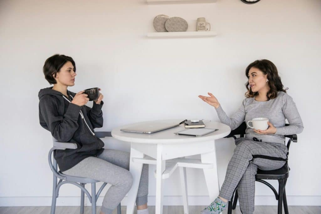 Two women enjoying a casual conversation with coffee in a cozy indoor setting, enhancing connections.
