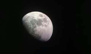 Stunning close-up of the half moon captured in a dark night sky, showcasing lunar craters and surface details.