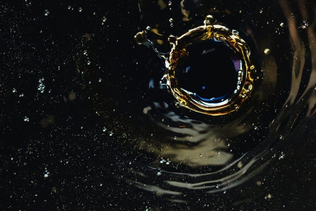 Close-up abstract capture of a water droplet splash with golden reflections on a dark background.